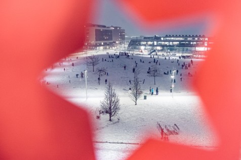 Erwachsene und Kinder stehen und spielen am schneebedeckten Hannah-Aredt-Platz. 